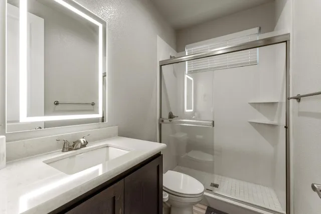 a bathroom with a granite countertop sink toilet and shower