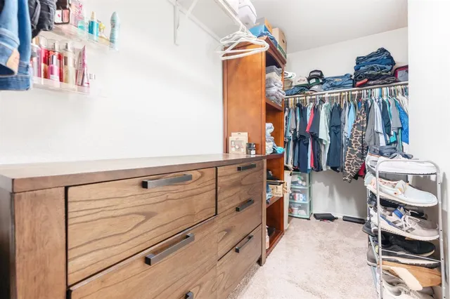 a view of walk in closet with clothes and shoes