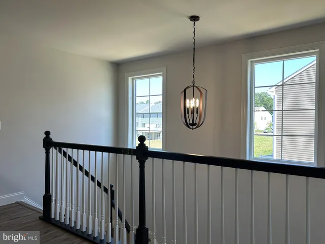 a view of a hallway with windows stairs and a chandelier fan