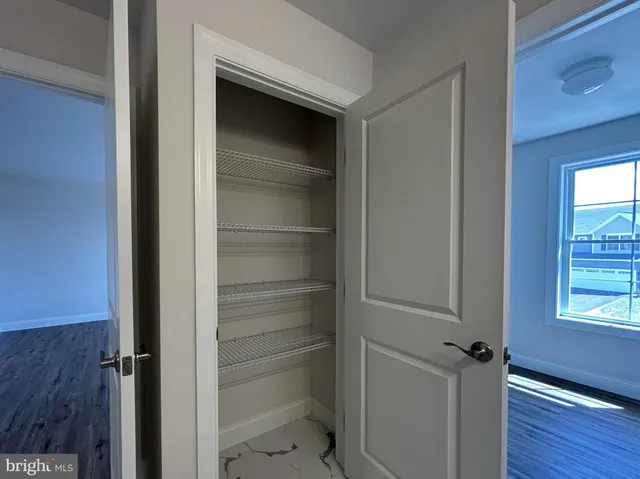 a view of a hallway with wooden floor and closet area