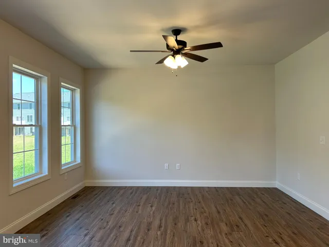 an empty room with wooden floor fan and windows