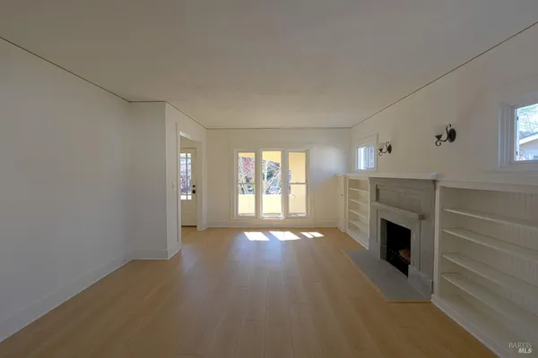 a view of an empty room with a fireplace and a window