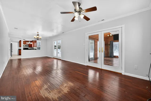 a view of an empty room with wooden floor and a ceiling fan