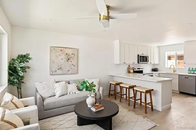 a living room with furniture kitchen view and a potted plant
