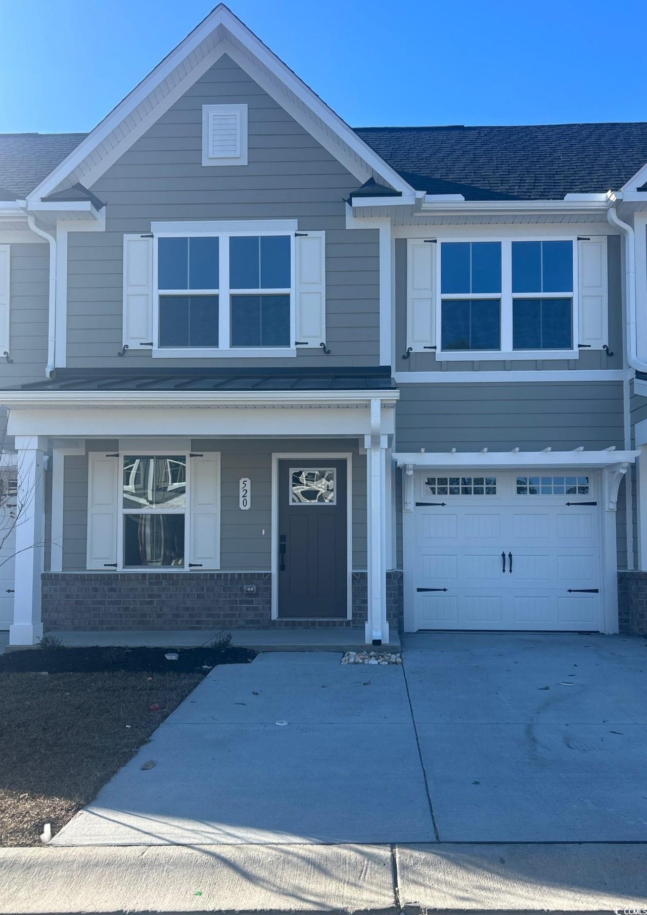 View of front facade with a porch, brick siding, concrete driveway, and an attached garage