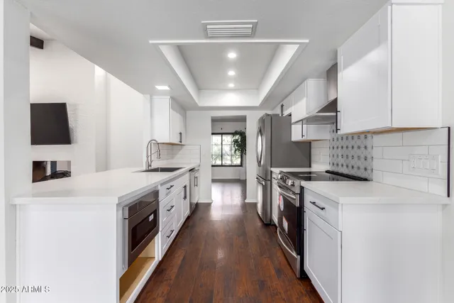 a kitchen with stainless steel appliances a refrigerator a sink and white cabinets