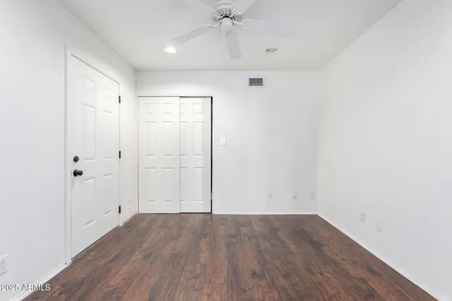 an empty room with windows and fan