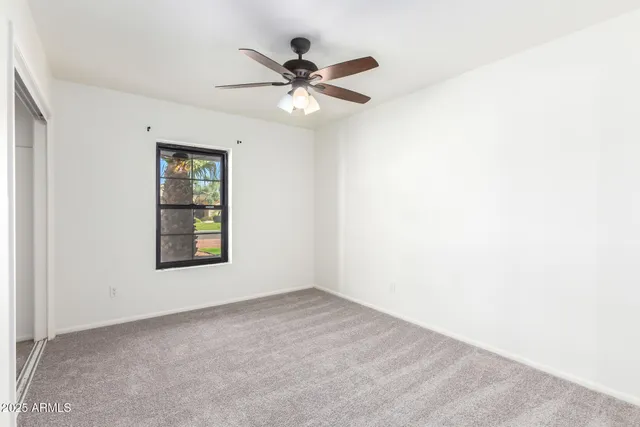 an empty room with a ceiling fan and a window