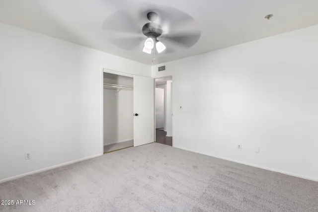 an empty room with windows and fan