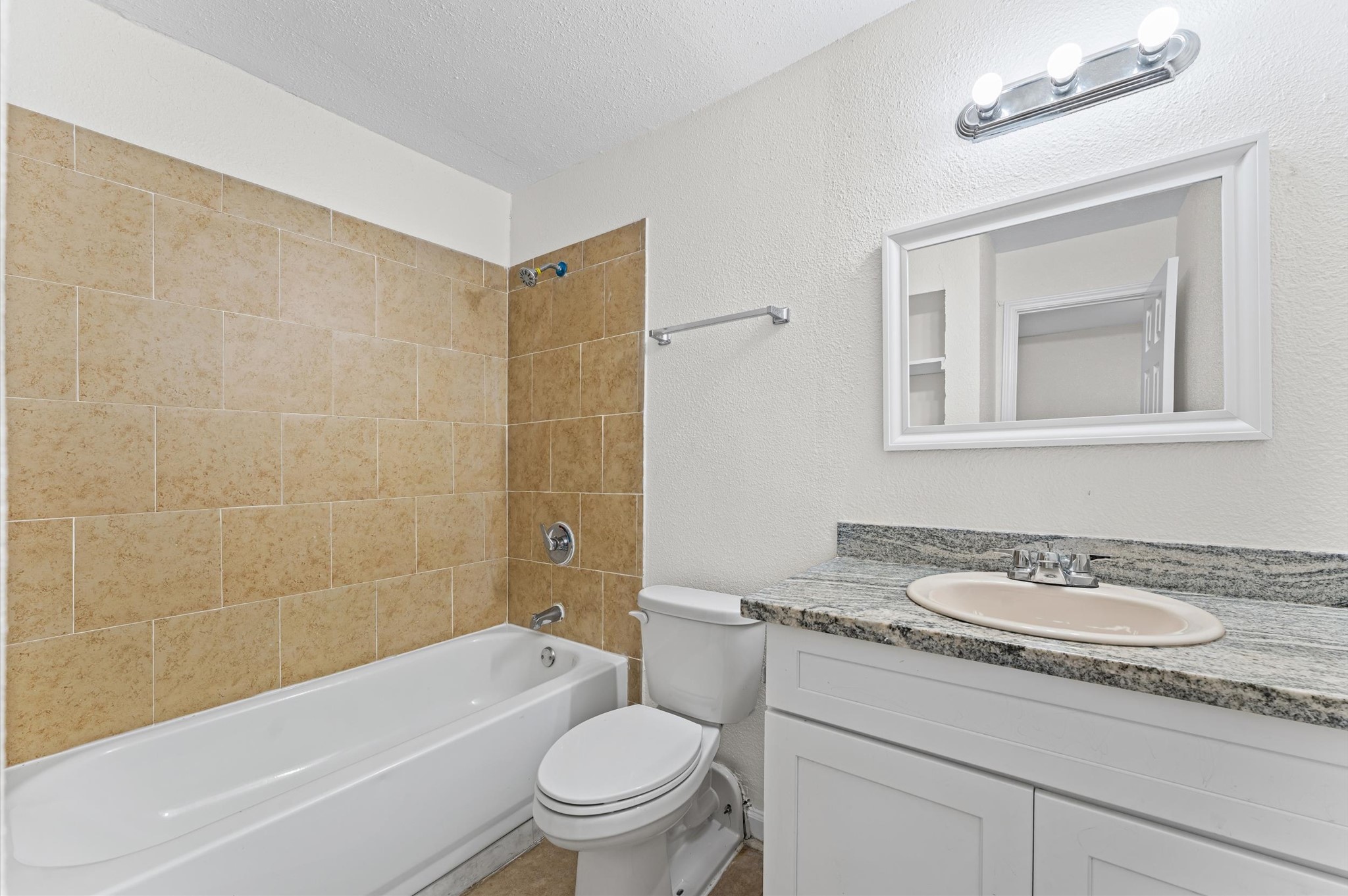 6161 Reims Road, Unit 906 Houston, TX 77036 - Photo 8 of 16 a bathroom with a granite countertop sink a toilet a mirror a bathtub and shower