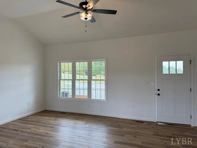 an empty room with wooden floor fan and windows