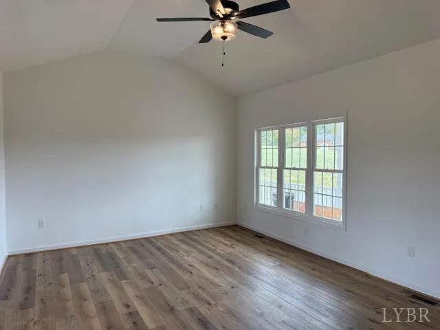 a view of an empty room with wooden floor fridge and a window