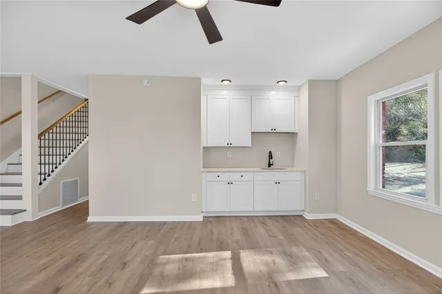 an empty room with wooden floor ceiling fan and windows