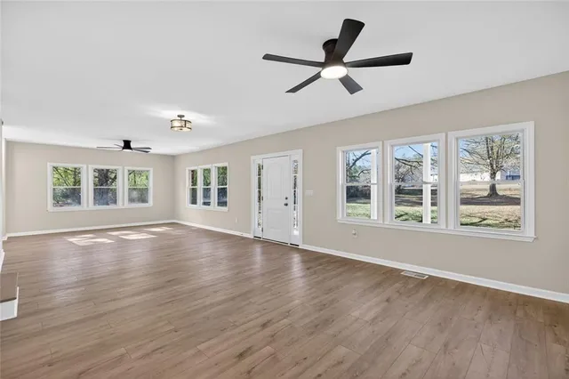 a view of an empty room with a window and wooden floor