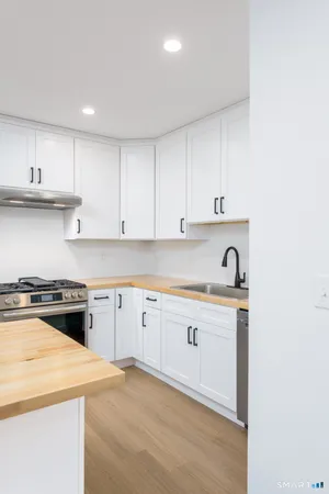 a kitchen with granite countertop a sink a stove and cabinets