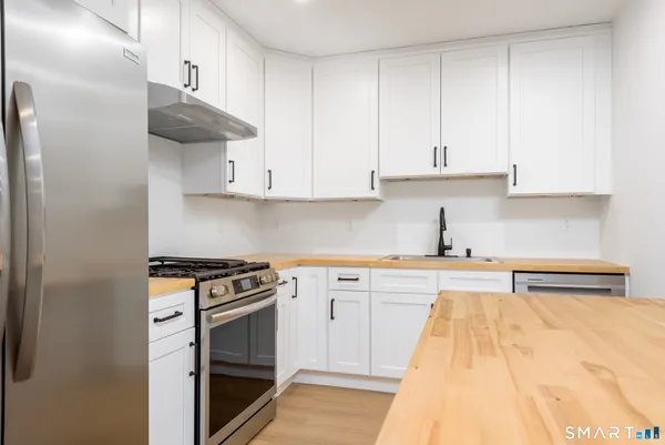 a kitchen with granite countertop white cabinets and stainless steel appliances