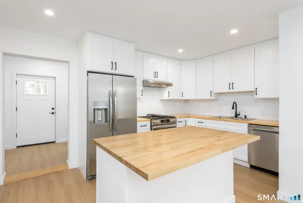 a kitchen with stainless steel appliances granite countertop a sink a stove a refrigerator a cabinets and wooden floor