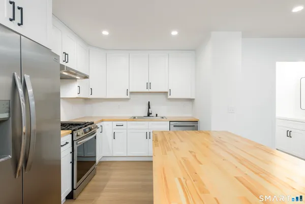 a kitchen with stainless steel appliances granite countertop a stove a refrigerator and a sink