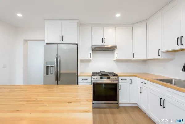 a kitchen with stainless steel appliances white cabinets and wooden floor