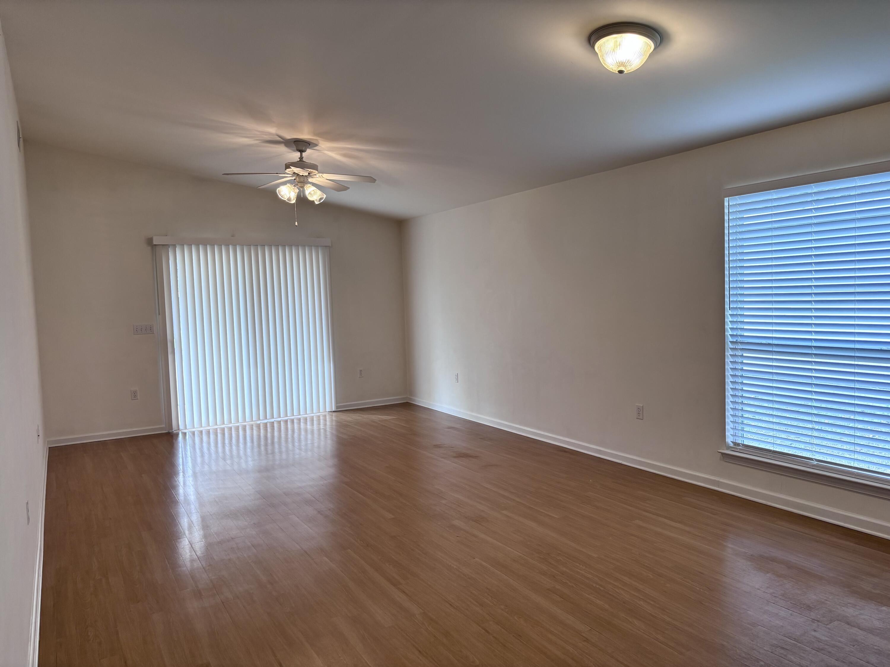 64 7th Street Shalimar, FL 32579 - Photo 4 of 16 an empty room with wooden floor chandelier fan and windows