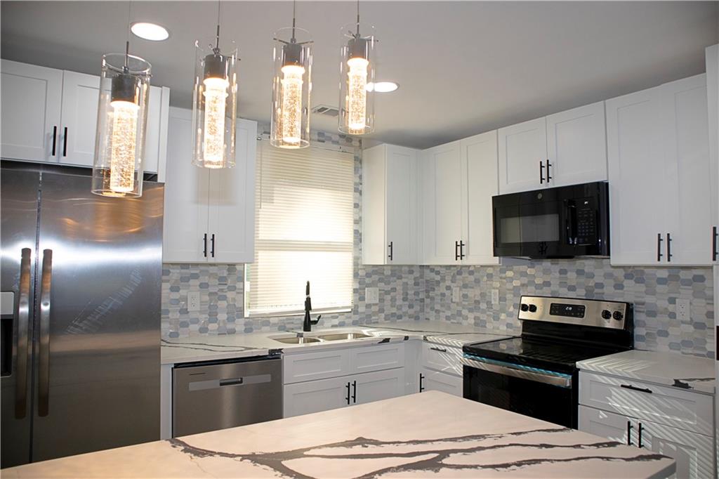 3162 Spring Drive Northwest Atlanta, GA 30360 - Photo 1 of 1 a kitchen with stainless steel appliances kitchen island granite countertop a sink stove and refrigerator