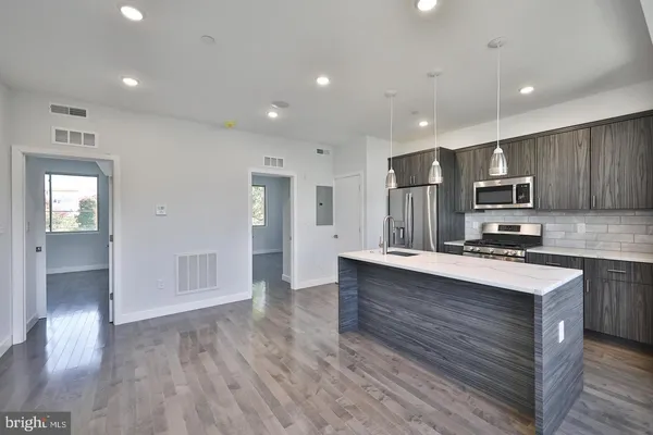 a large kitchen with stainless steel appliances granite countertop a large counter top and wooden floors