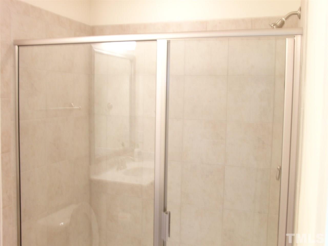 7893 Allscott Way Raleigh, NC 27612 - Photo 17 of 25 a bathroom with a glass shower door