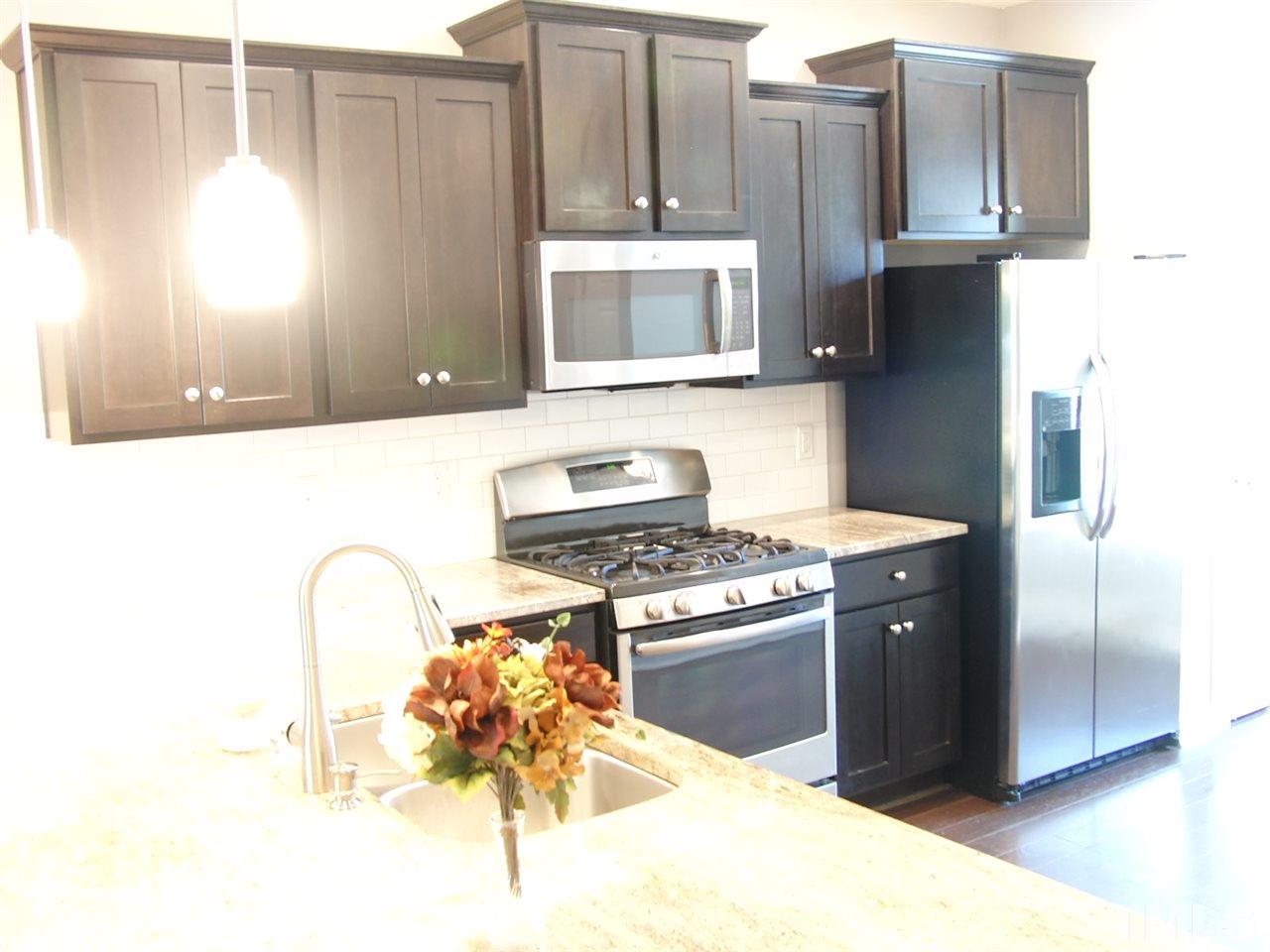 7893 Allscott Way Raleigh, NC 27612 - Photo 5 of 25 a kitchen with stainless steel appliances granite countertop a stove a refrigerator and a microwave