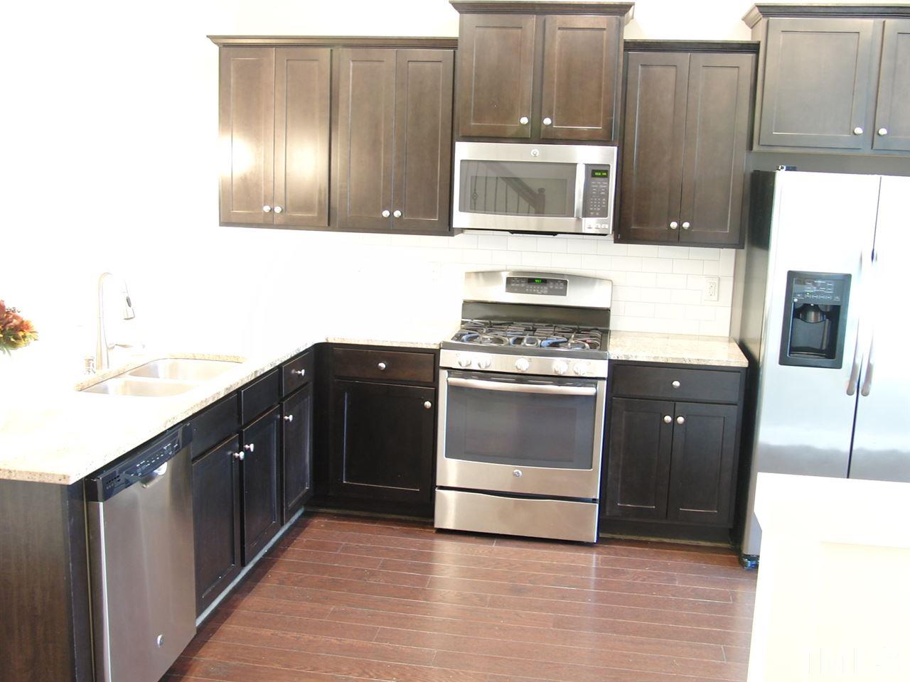 7893 Allscott Way Raleigh, NC 27612 - Photo 7 of 25 a kitchen with granite countertop a stove and a microwave