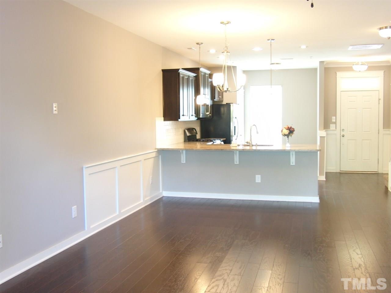 7893 Allscott Way Raleigh, NC 27612 - Photo 8 of 25 a view of a kitchen with kitchen island a sink wooden floor and counter top space