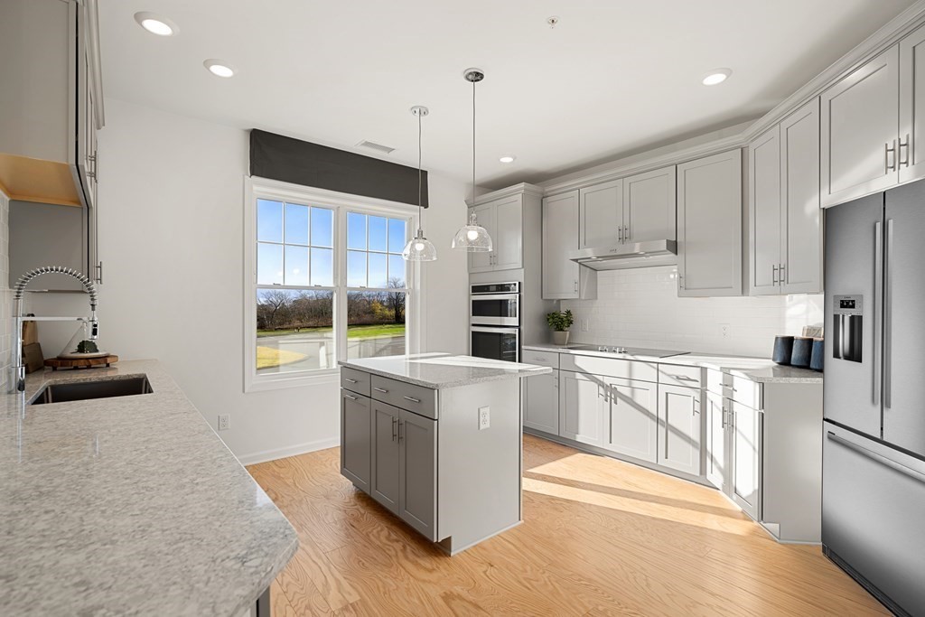 a kitchen with stainless steel appliances kitchen island wooden cabinets a stove a sink and a refrigerator