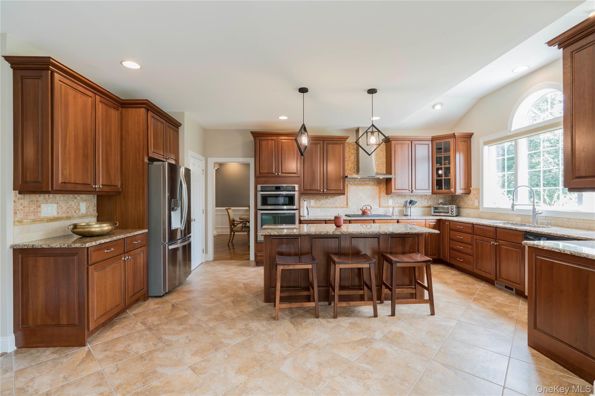 78 Moore Road Hopewell Junction, NY 12533 - Photo 14 of 38 Kitchen with backsplash, brown cabinets, a kitchen bar, appliances with stainless steel finishes, and a kitchen island