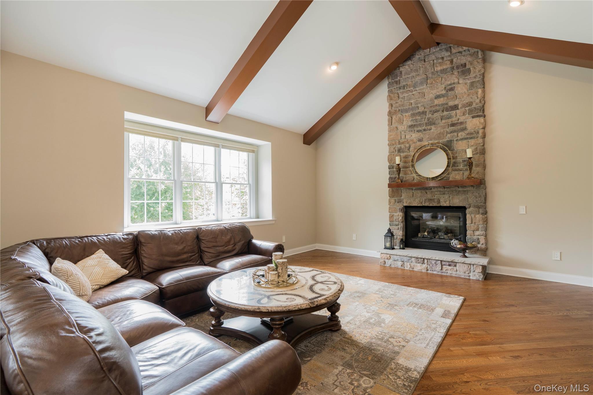 78 Moore Road Hopewell Junction, NY 12533 - Photo 18 of 38 Living room with beam ceiling, wood finished floors, a stone fireplace, and high vaulted ceiling