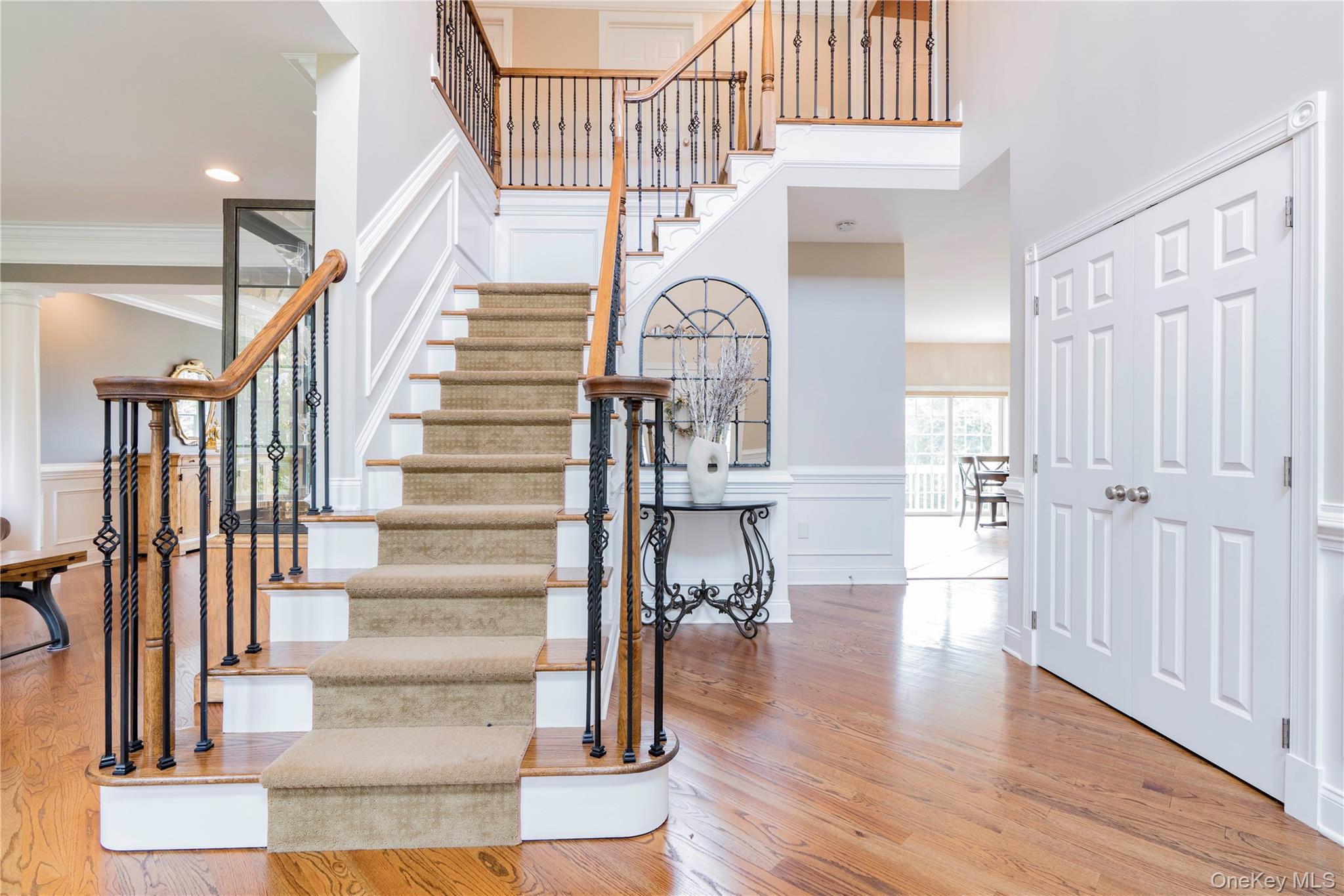 78 Moore Road Hopewell Junction, NY 12533 - Photo 3 of 38 Staircase featuring a decorative wall, wood finished floors, a wainscoted wall, ornamental molding, and a towering ceiling