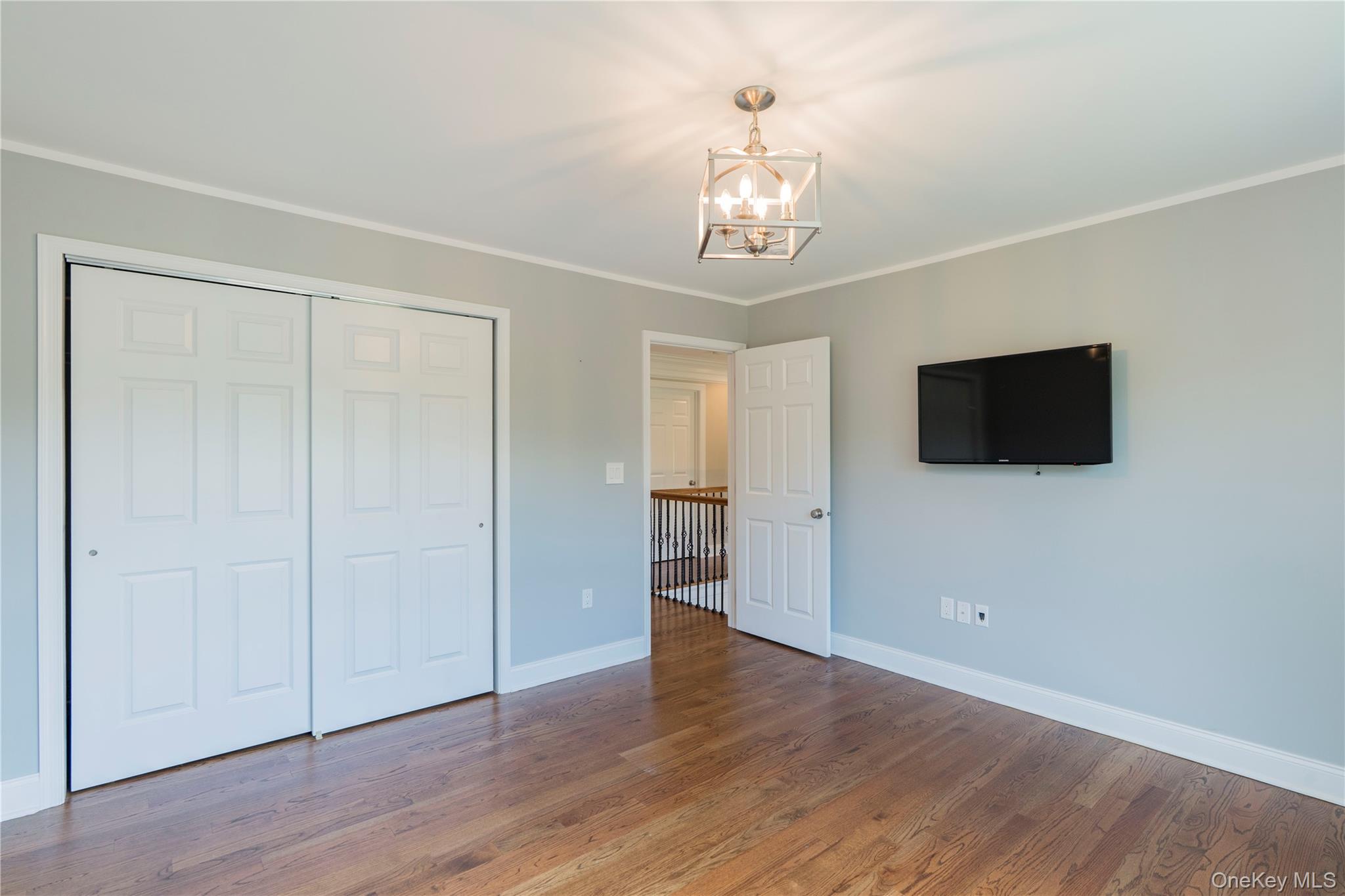 78 Moore Road Hopewell Junction, NY 12533 - Photo 31 of 38 Unfurnished bedroom featuring wood finished floors, crown molding, a closet, and a chandelier