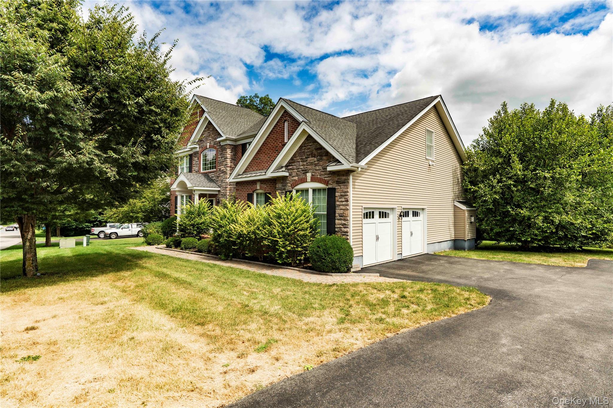 78 Moore Road Hopewell Junction, NY 12533 - Photo 33 of 38 View of home's exterior featuring stone siding, a lawn, an attached garage, asphalt driveway, and a shingled roof