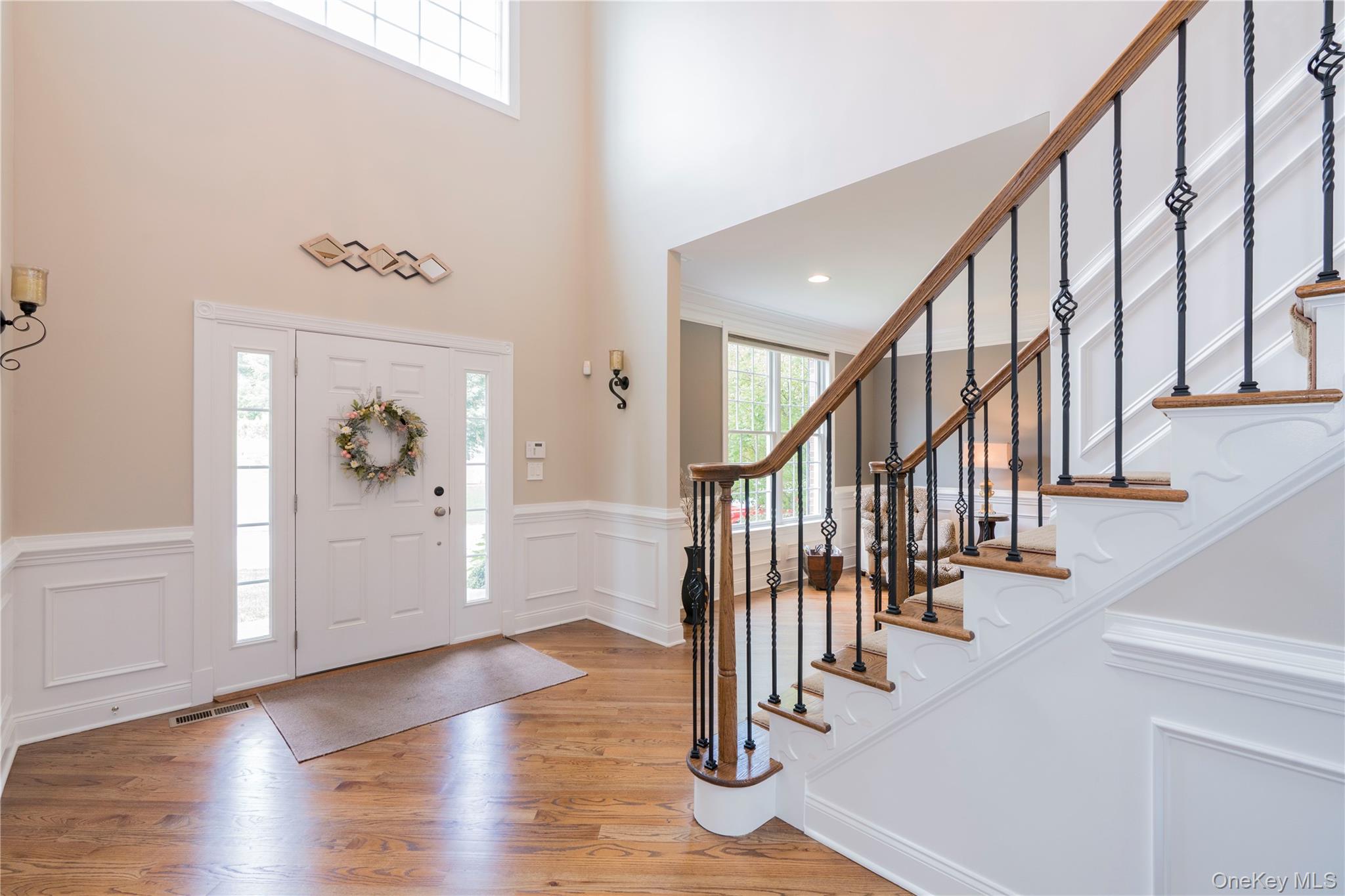 78 Moore Road Hopewell Junction, NY 12533 - Photo 5 of 38 Entryway featuring a towering ceiling, light wood-style flooring, a decorative wall, and a wainscoted wall