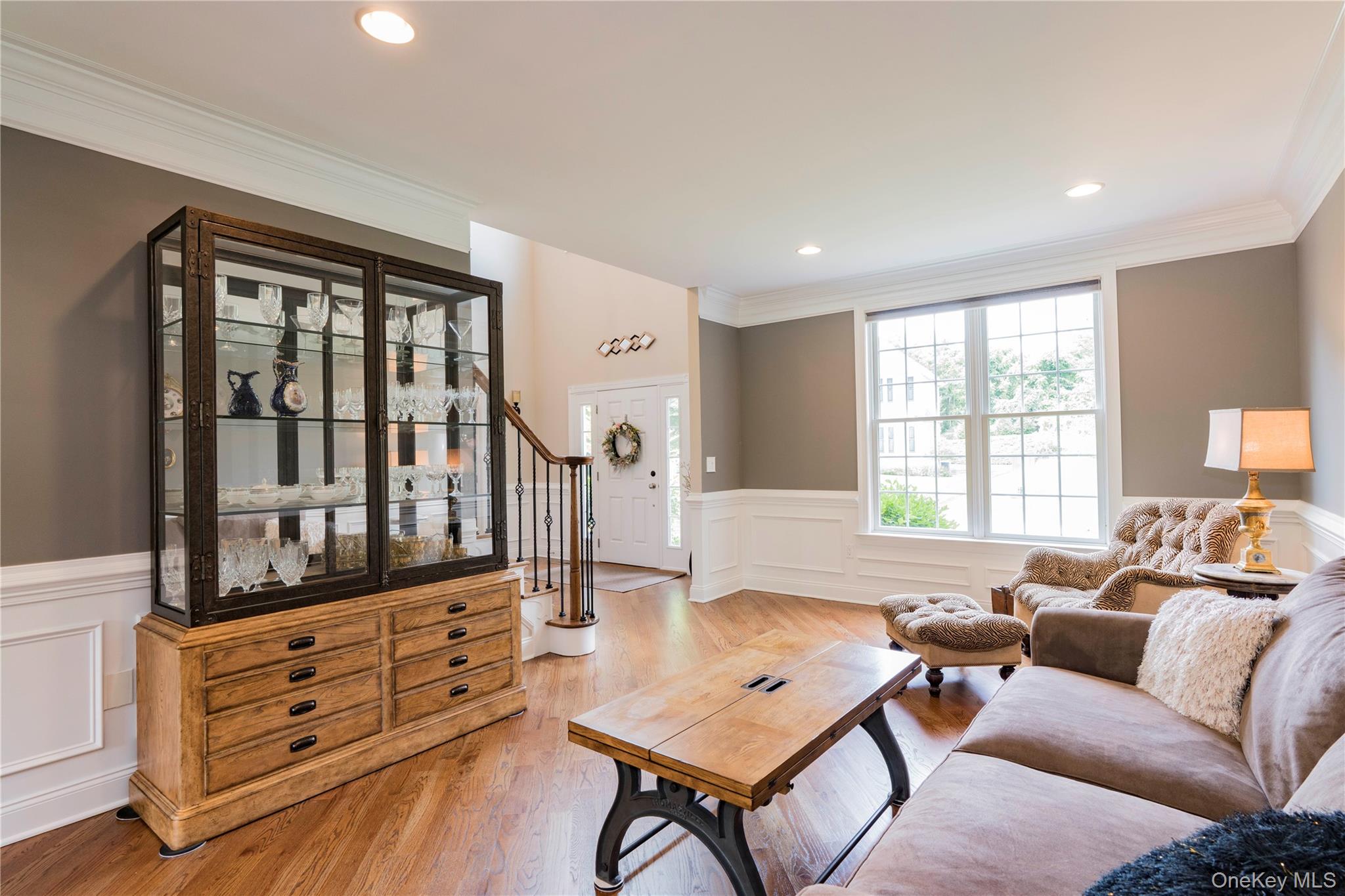 78 Moore Road Hopewell Junction, NY 12533 - Photo 7 of 38 Living area with wainscoting, a decorative wall, crown molding, light wood finished floors, and stairway