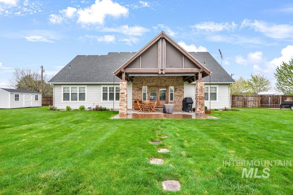 8271 Washoe Road Fruitland, ID 83619 - Photo 7 of 29 Spacious backyard featuring a covered patio with stone columns, a stepping stone path, and a storage shed