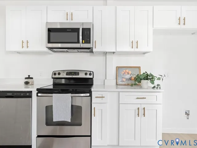 a kitchen with stainless steel appliances granite countertop white cabinets a microwave a sink and dishwasher