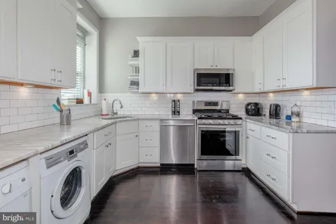 a kitchen with granite countertop white cabinets sink and stainless steel appliances