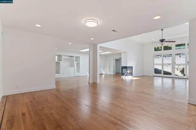 a view of an empty room with kitchen and window
