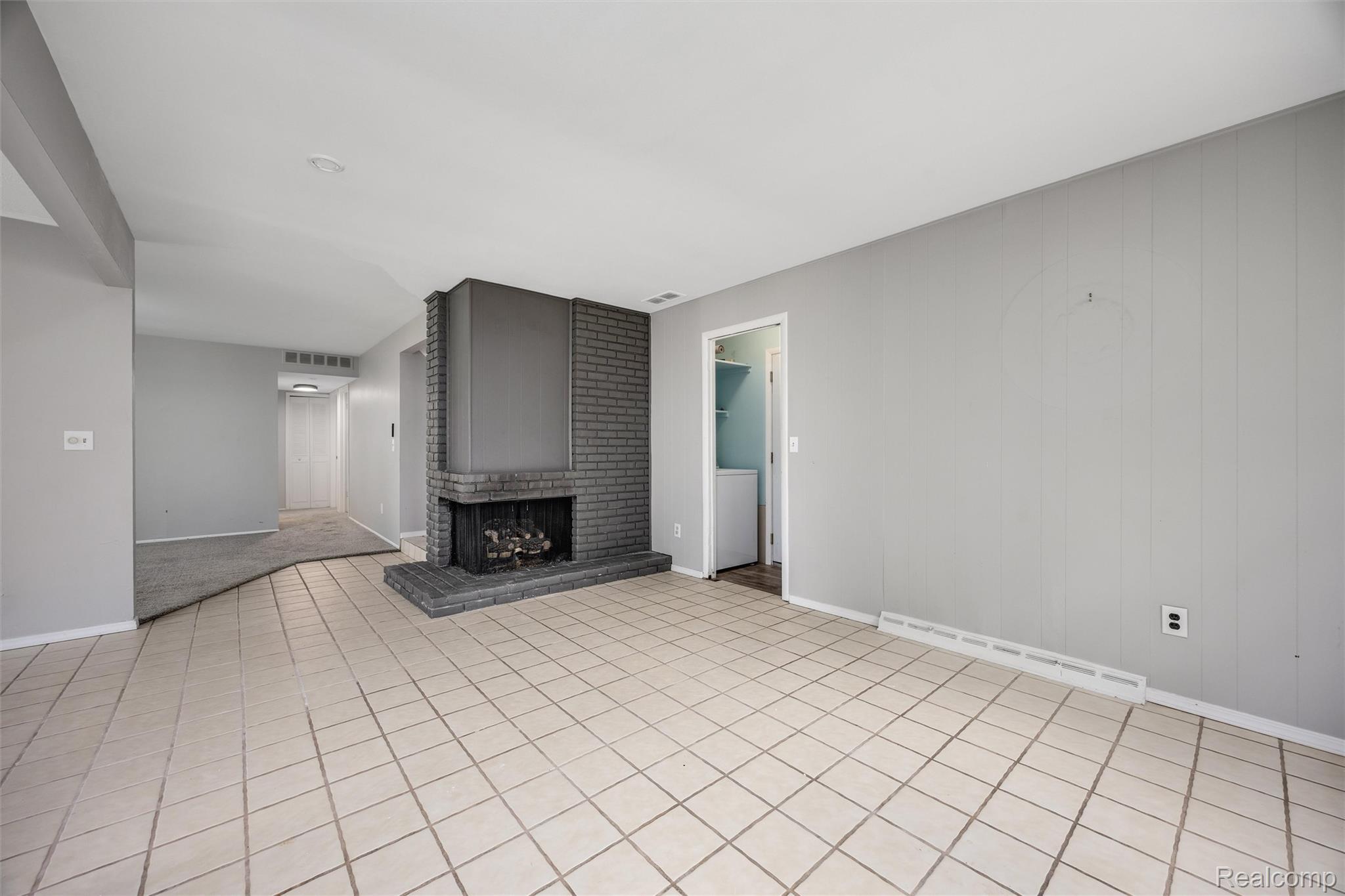 4942 Butler Drive Troy, MI 48085 - Photo 6 of 33 Living area featuring a brick fireplace with hearth, tile flooring, and a separate carpeted area