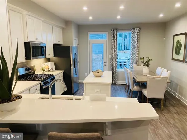 a kitchen with stainless steel appliances wooden floor dining table and chairs