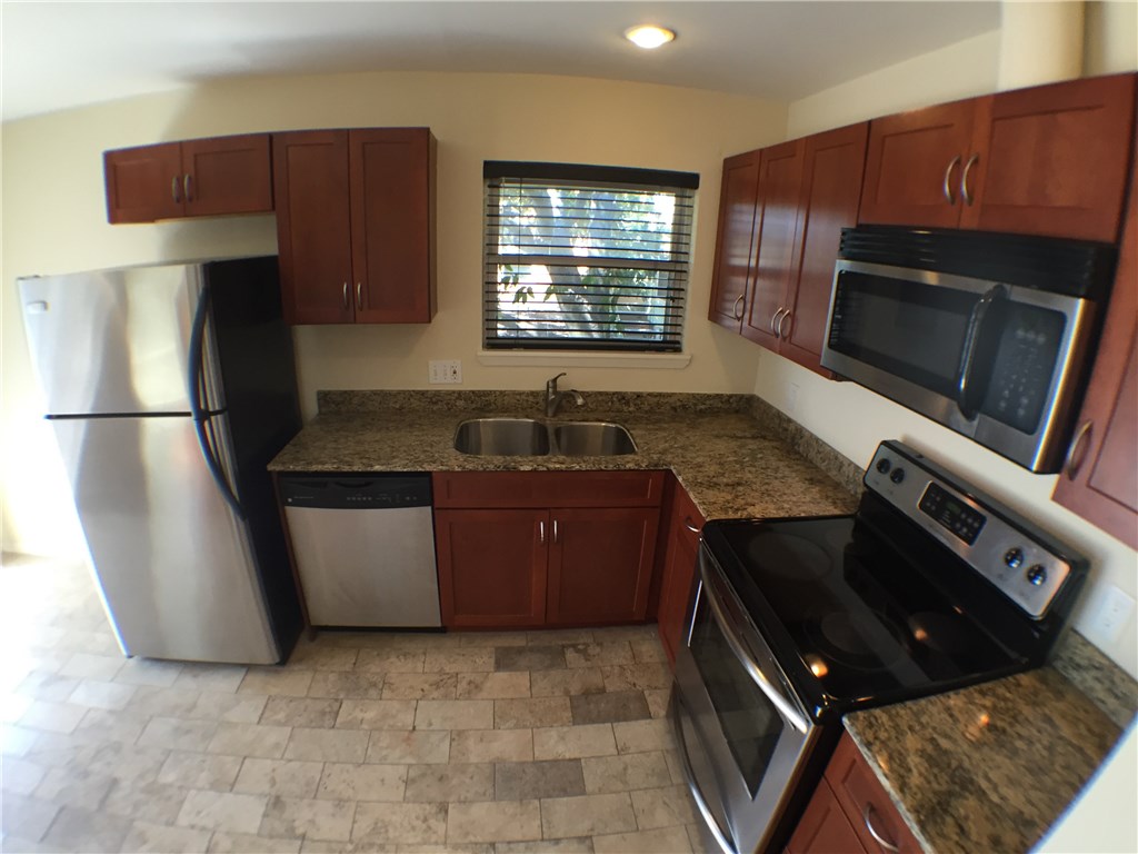 2800 Cole Street, Unit 201C Austin, TX 78705 - Photo 7 of 16 a kitchen with granite countertop a refrigerator stove and microwave
