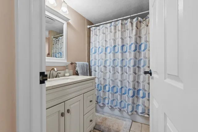 a bathroom with a granite countertop sink a mirror a vanity and a shower