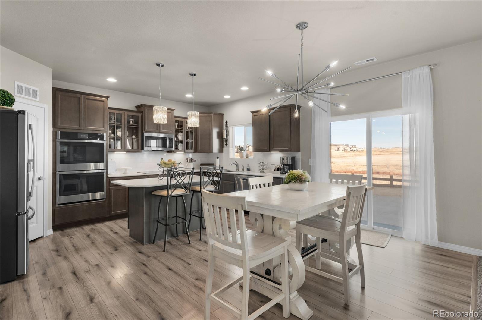 9033 Yellowtail Way Colorado Springs, CO 80908 - Photo 10 of 39 a kitchen with kitchen island a dining table chairs stainless steel appliances and cabinets