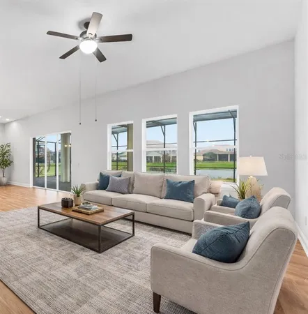 a living room with furniture ceiling fan and a large window