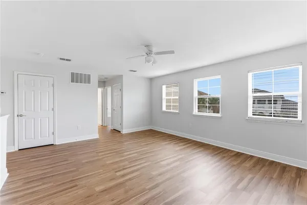 an empty room with wooden floor and windows