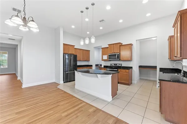 a kitchen with granite countertop a stove top oven a sink dishwasher and a refrigerator with wooden floor